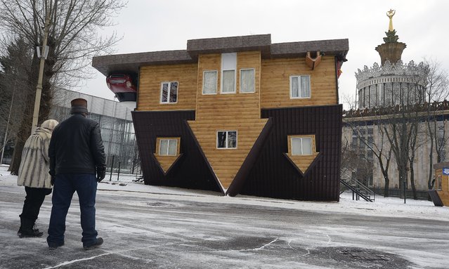 People look at an “upside-down house” attraction displayed at the All-Russia Exhibition Center in Moscow, on January 14, 2014. (Photo by Alexander Nemenov/AFP Photo)