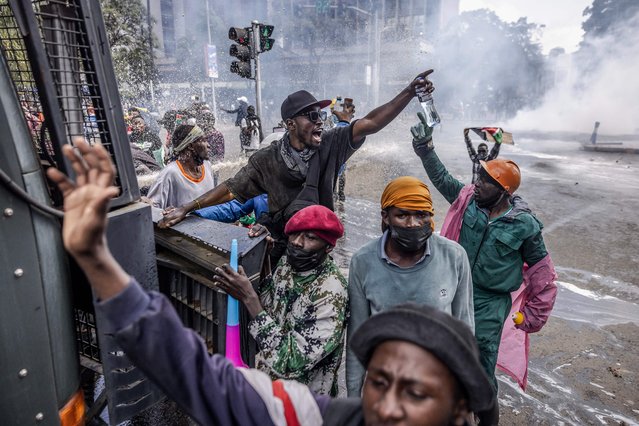 Protesters chant anti-government slogans as some of them climb a Kenya Police water cannon truck while demonstrating during a nationwide strike to protest against tax hikes and the Finance Bill 2024 in downtown Nairobi, on June 25, 2024. Kenyan police fired tear gas at crowds of young protesters in the capital Nairobi on Tuesday, according to AFP reporters, as demonstrators rallied across the country against the government's proposed tax hikes. The mainly Gen-Z-led rallies, which began last week, have taken President William Ruto's government by surprise, with the Kenyan leader saying over the weekend that he was ready to speak to the protesters. (Photo by Luis Tato/AFP Photo)