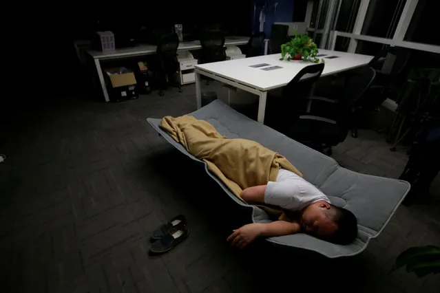 Ma Zhenguo, a system engineer at RenRen Credit Management Co., sleeps on a camp bed at the office after finishing work early morning, in Beijing, China, April 27, 2016. (Photo by Jason Lee/Reuters)