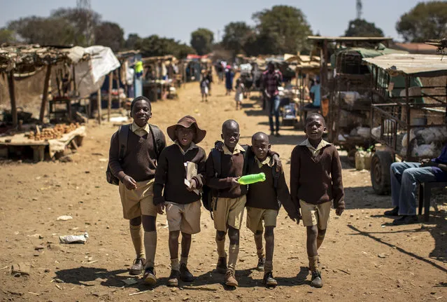 Schoolboys walk back home on the first day of the school term, in Kuwadzana, on the outskirts of the capital Harare, in Zimbabwe, September 10, 2019. Zimbabwe’s capital, Harare, a city of 1.5 million, bustles with activities of people scraping by, including street traders selling second-hand clothes, people striding to work past faded murals of Mugabe and women carrying baskets of laundry they had just washed in a muddy creek. (Photo by Ben Curtis/AP Photo/File)