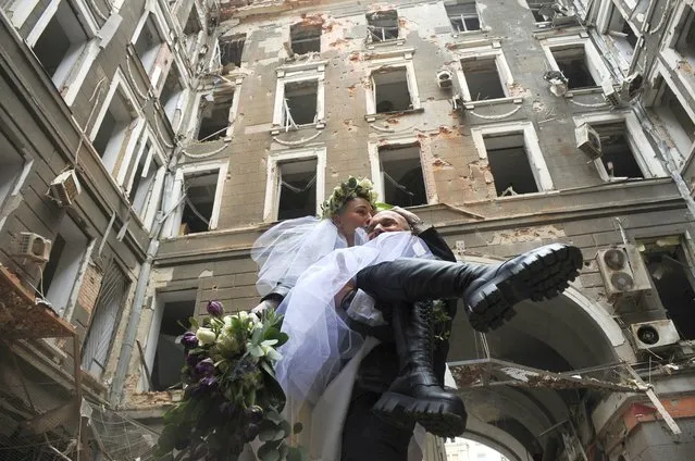 Volunteers Anastasia, left, and Anton pose for a picture in a yard of an apartment building destroyed by shelling during their wedding celebration in Kharkiv, Ukraine, Sunday, April 3, 2022. (Photo by Andrew Marienko/AP Photo)