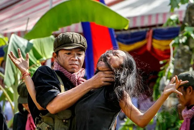Cambodian students from the Royal University of Fine Arts re-enact the torture executed by the Khmer Rouge during their reign of terror in the 1970s to mark the annual Day of Anger at Choeung Ek, a former Khmer Rouge “killing field” dotted with mass graves, on the outskirts of Phnom Penh, on May 20, 2014. (Photo by Heng Sinith/Associated Press)