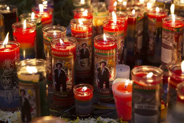 Candles with images of folk saint Maximon burn inside a church dedicated to him on the folk saint's feast day in San Andres Itzapa, Guatemala, Monday, October 28, 2019. Sometimes called San Simon, Maximon is a an indigenous character worshipped by Mayans in the highlands of Western Guatemala. He is portrayed as a human character who likes alcohol and cigarettes, and includes the homeless and prostitutes as some of his loyal followers. (Photo by Moises Castillo/AP Photo)