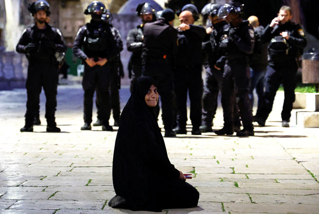 A Palestinian woman sits near Israeli border policemen in the Al-Aqsa compound, also known to Jews as the Temple Mount, while tension arises during clashes with Palestinians in Jerusalem's Old City on April 5, 2023. (Photo by Ammar Awad/Reuters)