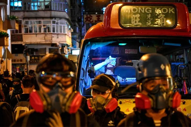 Protesters wear masks as a mini bus driver uses a paper towel to cover his face after police fire tear gas at the Jordan area during a march towards Hong Kong Polytechnic University in Hong Kong on November 18, 2019. Dozens of Hong Kong protesters escaped a two-day police siege at a campus late November 18 by shimmying down a rope from a bridge to awaiting motorbikes in a dramatic and perilous breakout that followed a renewed warning by Beijing of a possible intervention to end the crisis engulfing the city. (Photo by Philip Fong/AFP Photo)