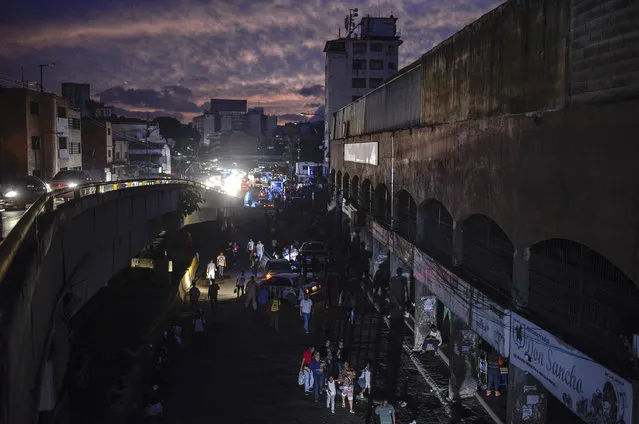 People are seen in the streets of Petare neighbourhood after Caracas and other parts of Venezuela were hit by a massive power cut on July 22, 2019. The lights went out in most of Caracas causing traffic jams and sending people back home on foot after the metro stopped running, while people in other parts of the country took to social media to report the power had gone out there too. The state-owned power company CORPOELEC only reported a breakdown affecting sectors of Caracas. (Photo by Matias Delacroix/AFP Photo)