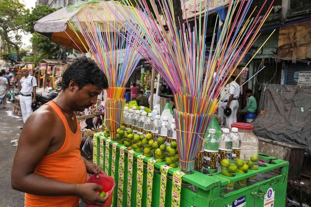 A lemon water seller arranges his cart at a roadside in Kolkata, India, Thursday, April 14, 2022. (Photo by Bikas Das/AP Photo)