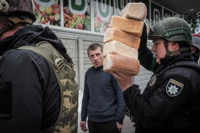 Police officers deliver loaves of bread for the residents staying in the eastern Ukraine city of Lyman received heavy shelling, on May 2, 2022, as Russian forces continued their push into eastern Ukraine on May 1, killing eight civilians in rocket attacks in Donetsk and Kharkiv, the regions' governors said. Lyman, a former railway hub known as the “red town” for its redbrick industrial buildings, is expected to be one of the next places to fall after Ukrainian forces withdrew. (Photo by Yasuyoshi Chiba/AFP Photo)