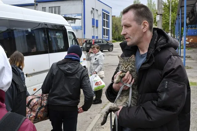 A man holds a cat as people board transport during an evacuation of civilians in Kramatorsk, Ukraine, Saturday, April 30, 2022. (Photo by Andriy Andriyenko/AP Photo)