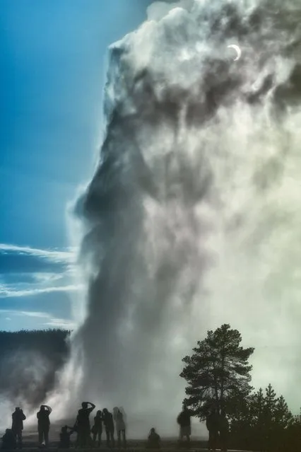 Eclipse and Old Faithful by Robert Howell (USA). Visitors witness the Old Faithful geyser in Yellowstone National Park erupt as the Moon partially eclipses the Sun. The scene captures a sense of awe set against blue sky and white geyser steam, as the onlookers strain to see the joining of these two phenomena – one geological and one astronomical. (Photo by Robert Howell)