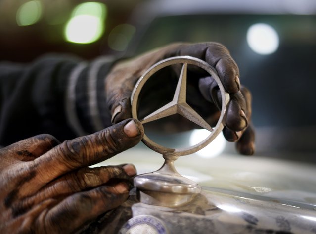 A mechanic replaces a sing on a 1976 Mercedes at a private collector's lot in El Saff city in the Giza, just outside Cairo, Egypt. Friday, April 8, 2022. Egyptian businessman and a classic car collector Mohamed Wahdan says he has accumulated more than 250 vintage, antique and classic cars over the past 20 years. (Photo by Amr Nabil/AP Photo)
