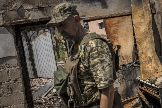 Commander of an artillery unit of the Ukrainian army, Mykhailo Strebizh, center, inside a destroyed house due to shelling in a village near the frontline in the Donetsk oblast region, eastern Ukraine, Thursday, June 2, 2022. (Photo by Bernat Armangue/AP Photo)