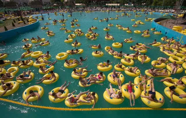People cool off as they bathe at the aqua-park swimming pool in Minsk, Belarus, on Sunday, Aug. 9, 2015.  Temperatures in the capital have reached around 32 degrees Celsius (89,6 F), drawing large crowds to the water park over the weekend. (Photo by Yauhen Leonov/AP Photo)
