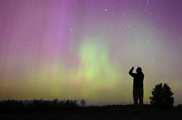 The Aurora Borealis, also known as the "Northern Lights", illuminate the sky as people gather to watch the annual Perseid meteor shower near the village of Borodinka in the Omsk region, Russia on August 13, 2024. (Photo by Alexey Malgavko/Reuters)