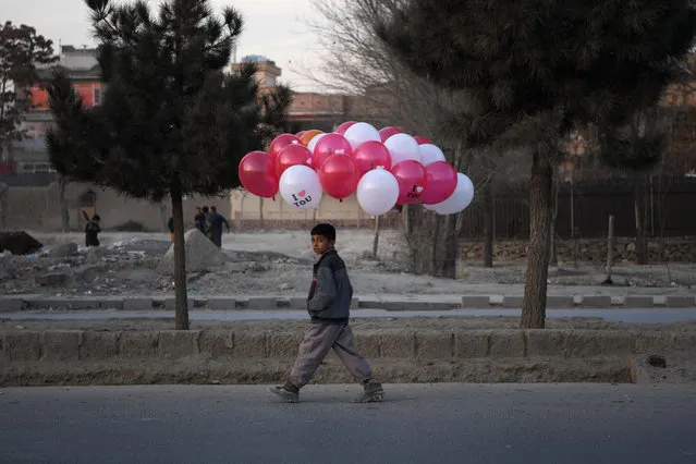 An Afghan child walks with balloons he is selling on a street in Kabul on December 23, 2019. (Photo by Farshad Usyan/AFP Photo)