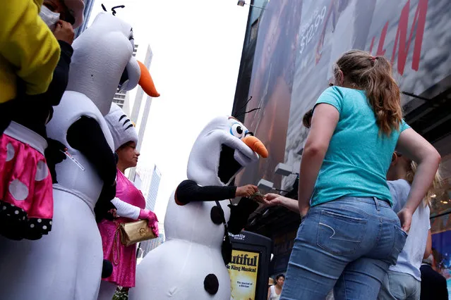 Costumed characters take tips after taking photographs with tourists in Times Square while working within new zones designated for street performers to solicit tips for their services in New York, U.S., June 21, 2016. (Photo by Lucas Jackson/Reuters)