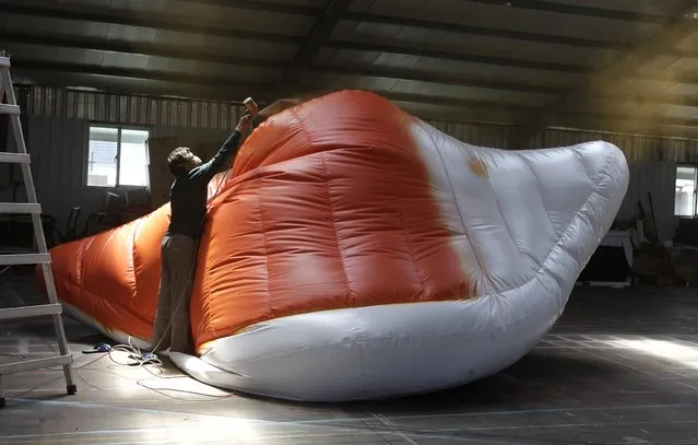 A worker sprays paint on the beak of the “Rubber Duck” inflatable floating sculpture by Dutch conceptual artist Florentijn Hofman at a factory in New Taipei City September 5, 2013. The giant “Rubber Duck”, measuring 18 metres in height and weighing 1000 kilogrammes when completed, will be displayed in Kaohsiung port, southern Taiwan. (Photo by Pichi Chuang/Reuters)