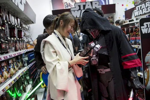 A fan smiles as she picks new toys from the upcoming film “Star Wars: The Force Awakens” on “Force Friday” in Hong Kong, China, September 4, 2015. (Photo by Tyrone Siu/Reuters)