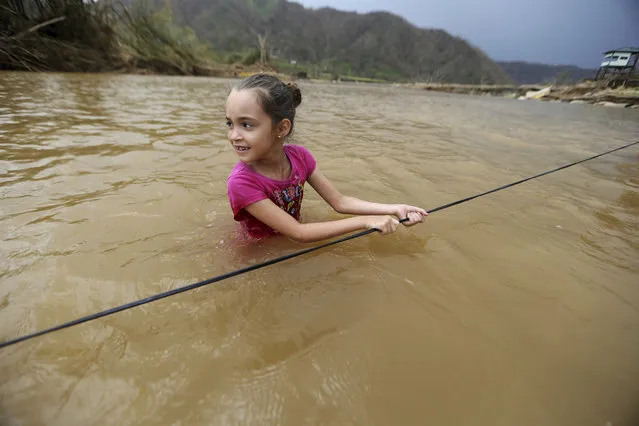 Ruby Rodriguez, 8, looks back at her mother as she wades across the San Lorenzo Morovis river with her family, since the bridge was swept away by Hurricane Maria, in Morovis, Puerto Rico, Wednesday, September 27, 2017. They were returning to their home after visiting family on the other side. (Photo by Gerald Herbert/AP Photo)