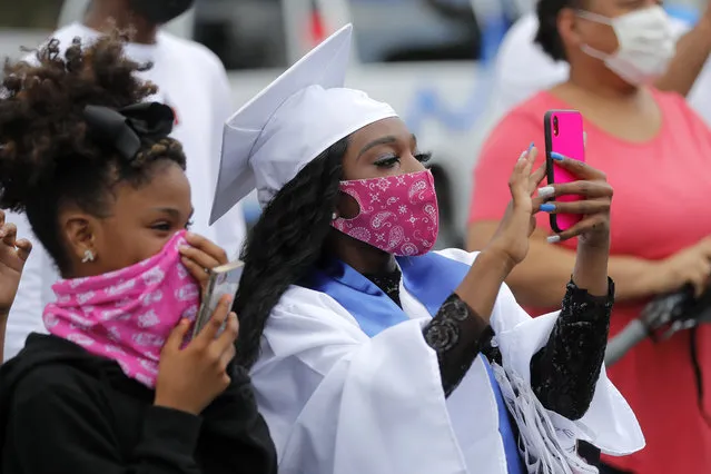 Masked graduates and guests take photos as the New Orleans Charter Science and Math High School class of 2020 holds a drive-in graduation ceremony as a result of the COVID-19 pandemic, outside Delgado Community College in New Orleans, Wednesday, May 27, 2020. Students and family got out of their cars to receive diplomas one by one, and then held a parade of cars through city streets. (Photo by Gerald Herbert/AP Photo)