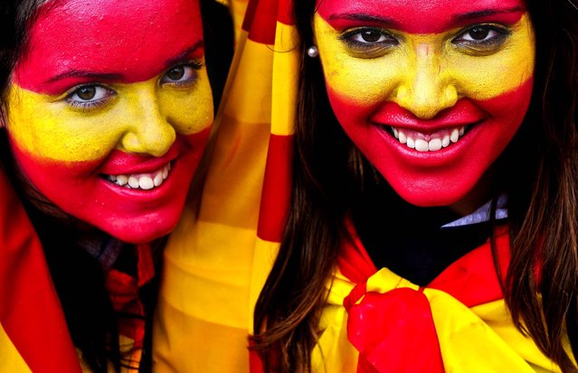 Women with their faces painted with the color of the Spanish flag celebrate National Day in Barcelona, on October 12, 2012. (Photo by Manu Fernandez/Associated Press)