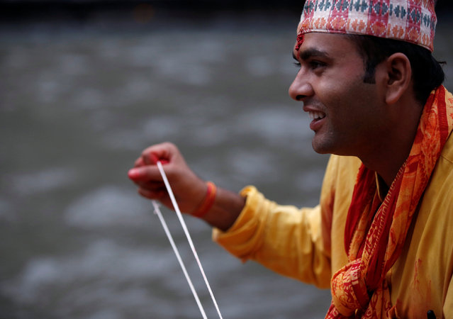 A Hindu priest holds a sacred thread during the Janai Purnima (Sacred Thread) Festival at Pashupatinath temple in Kathmandu, Nepal, August 18, 2016. (Photo by Navesh Chitrakar/Reuters)