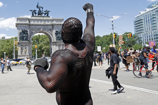 A man raises his fist as a group of Black Lives Matter marchers approached Brooklyn's Grand Army Plaza ast the beginning of a Caribbean-led rally, Sunday, June 14, 2020, in New York. Protests have grown since the May 25th death of George Floyd, a black man who died inn police custody in Minneapolis after a white police officer pressed his knee into Floyd's neck for nearly nine minutes. (Photo by Kathy Willens/AP Photo)