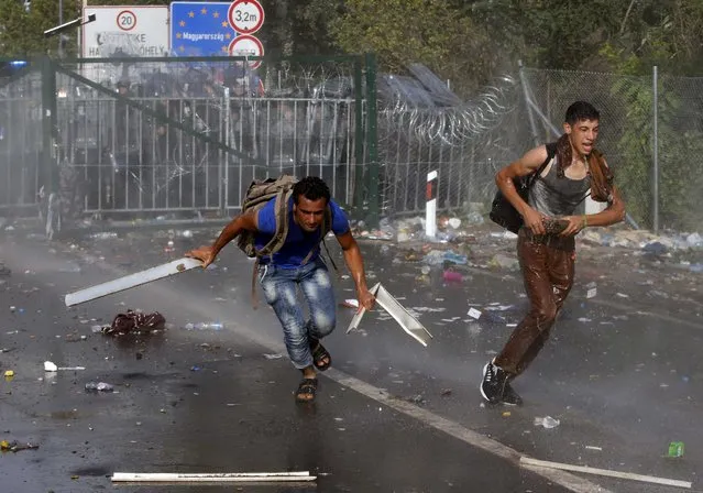 Migrants protest as Hungarian riot police fires tear gas and water cannon at the border crossing with Serbia in Roszke, Hungary September 16, 2015. (Photo by Marko Djurica/Reuters)