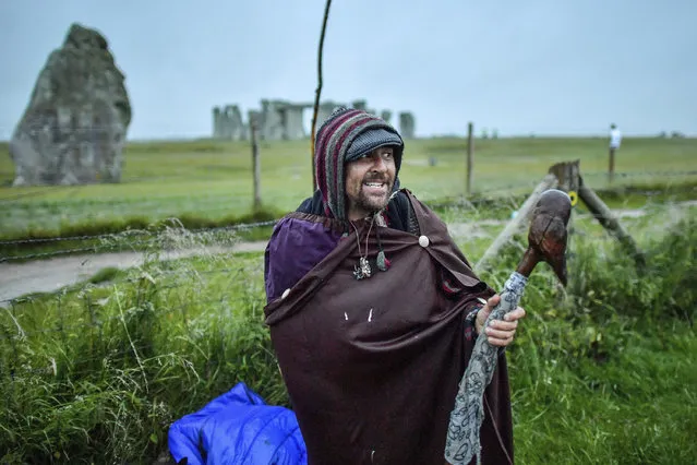 A man stands beside a barbed wire fence next to the closed Stonehenge as people gather to celebrate the dawn of the longest day, the Summer Solstice, near Salisbury, England, Sunday June 21, 2020. (Photo by Ben Birchall/PA Wire via AP Photo)