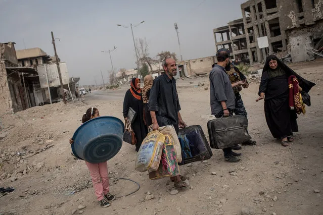 Civilians carry their belongings on a destroyed street in an outer neighborhood of the Old City in West Mosul on November 6, 2017 in Mosul, Iraq. (Photo by Chris McGrath/Getty Images)
