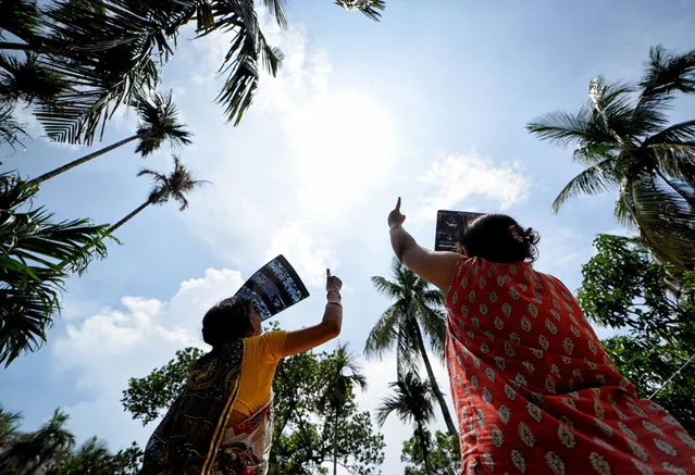 Two woman seen observing the solar eclipse from a terrace using an X ray plate in Kolkata, India on June 21, 2020. The partial solar eclipse in Kolkata will last for approximately three hours and 31 minutes. It began at 10:46 am local time and will end at 2:17 pm during this period around 67% of Sun will be covered by the shadow of Moon. (Photo by Avishek Das/SOPA Images/Rex Features/Shutterstock)