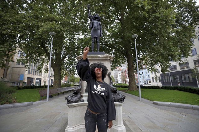 Jen Reid poses for photographs in front of the new black resin and steel statue portraying her, entitled “A Surge of Power (Jen Reid) 2020” by artist Marc Quinn after the statue was put up this morning on the empty plinth of the toppled statue of 17th century slave trader Edward Colston, which was pulled down during a Black Lives Matter protest in Bristol, England, Wednesday, July 15, 2020. On June 7 anti-racism demonstrators pulled the 18-foot (5.5 meter) bronze likeness of Colston down, dragged it to the nearby harbor and dumped it in the River Avon – sparking both delight and dismay in Britain and beyond. (Photo by Matt Dunham/AP Photo)