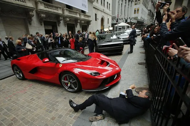 A man tries to take a picture of a Ferrari LaFerrari sports car parked at the entrance of the New York Stock Exchange in New York, October 13, 2014. Investors cautiously greeted the Wall Street debut on Monday of Fiat Chrysler Automobiles (FCA) , a move that shifts the carmaker's center of gravity away from Italy and caps a decade of canny dealmaking and tough restructuring by Chief Executive Sergio Marchionne. (Photo by Eduardo Munoz/Reuters)