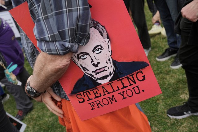 A demonstrator holds a sign featuring an image of Elon Musk, during a 'Hands Off!' protest against U.S. President Donald Trump and his adviser Elon Musk, on the Washington Monument grounds in Washington, D.C., U.S., April 5, 2025. (Photo by Ken Cedeno/Reuters)