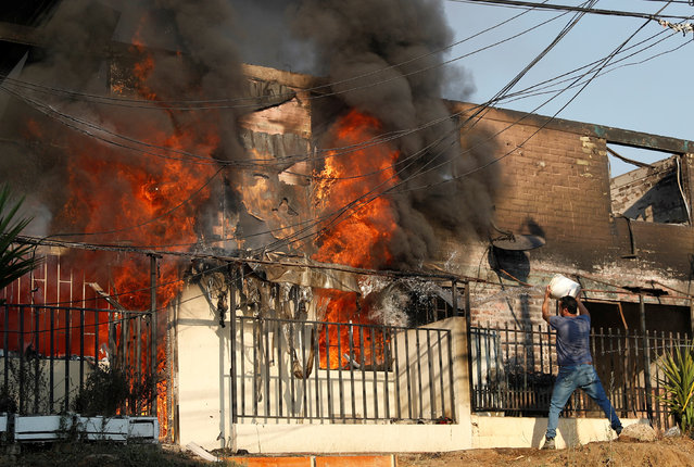 A man tries to extinguish a fire burning a house during the spread of wildfires in Vina del Mar, Chile on February 3, 2024. (Photo by Rodrigo Garrido/Reuters)