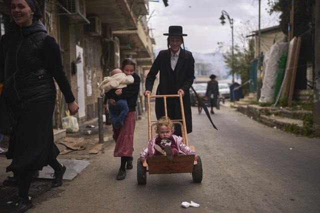 A child is transported on a dolly in the Orthodox neighborhood of Mea Shearim in Jerusalem during final preparations for the Passover holiday, April 11, 2025. (Photo by Ohad Zwigenberg/AP Photo)