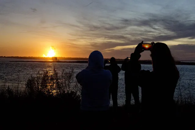 Spectators in Chincoteague, Va. watch the fireball from the explosion of the unmanned Orbital Sciences Corp.'s Antares rocket and Cygnus cargo capsule seconds after liftoff from Wallops Island, Va. on Tuesday, October 28, 2014. No injuries were reported following the first catastrophic launch in NASA's commercial spaceflight effort. (Photo by Rich-Joseph Facun/AP Photo/The Virginian-Pilot)