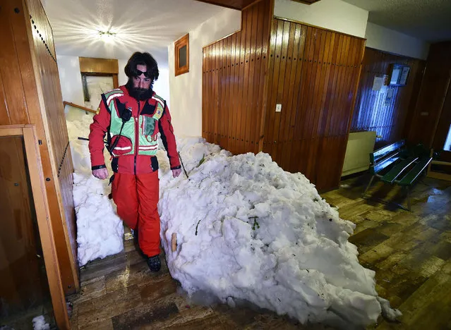 A paramedic inspects an apartment building covered with snow after Snow an avalanche hit in the Alpine town of Sestriere, near Turin, Italy, 09 January 2018. The authorities have evacuated 69 people, including several children, who have been put up in hotels, with the local council footing the bill. The building has been declared unfit for access. In addition, in the same town on 09 January roughly 100 people were evacuated from the Olympic Village built for the 2006 Winter games. Authorities have issued a high avalanche alert due to heavy snowfalls in northern Italy. (Photo by Alessandro Di Marco/EPA/EFE)