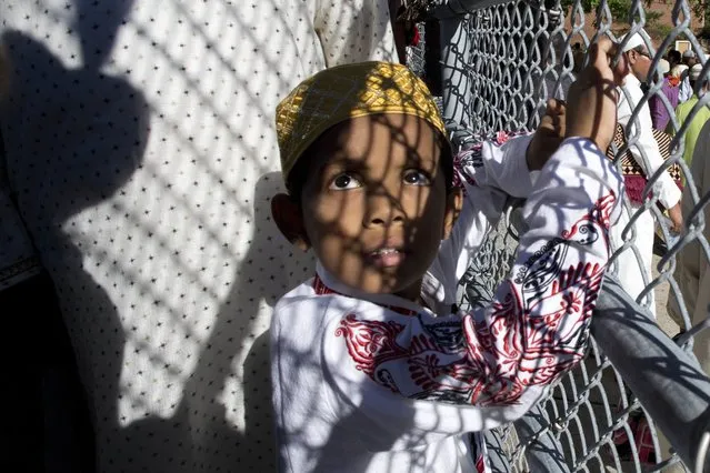 A Muslim boy looks through a fence following a service for the Eid al-Adha holiday, Monday, September 12, 2016, in the Queens borough of New York. (Photo by Mark Lennihan/AP Photo)
