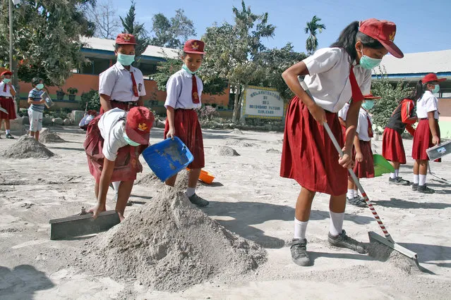 Students clean their school yard from ash after Mount Sinabung volcano erupted on Monday at Payung village in Karo, North Sumatra, Indonesia February 20, 2018. (Photo by Ahmad Putra/Reuters/Antara Foto)
