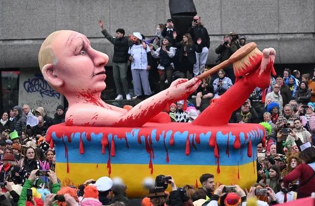 A carnival float featuring Russia's President Vladimir Putin taking a blood bath in a yellow-blue bathtub is pictured during a Rose Monday street carnival parade in Duesseldorf, western Germany, on February 20, 2023. (Photo by Ina Fassbender/AFP Photo)