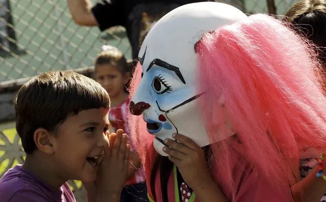 A boys speaks to his mask-wearing brother at a parade during the National Encounter of Mask festival in Barva de Heredia, October 30, 2015. (Photo by Juan Carlos Ulate/Reuters)