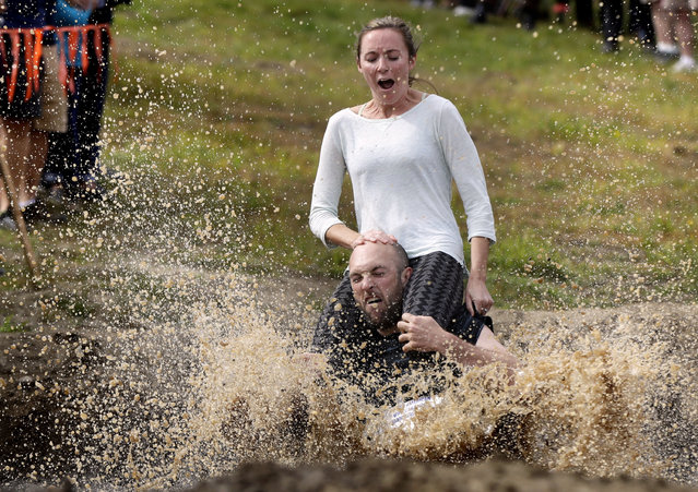 Peter Ver Ploeg carries Virginia Petrovek through the mud pit during the North American Wife Carrying Championship, Saturday, October 8, 2016, at the Sunday River Ski Resort in Newry, Maine. (Photo by Robert F. Bukaty/AP Photo)