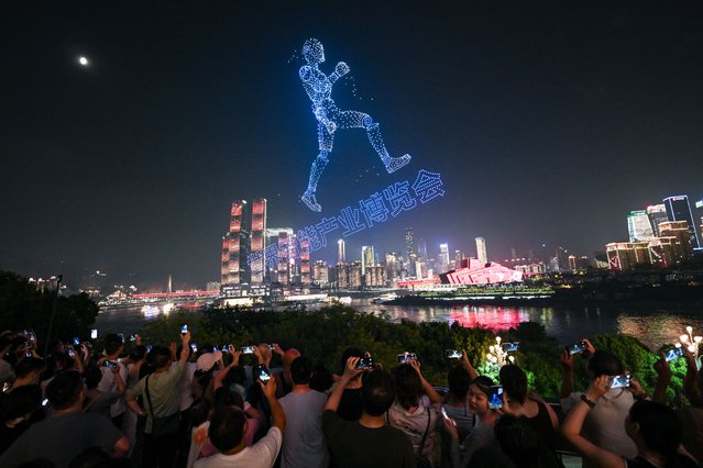 Visitors are attracted by a drone show before the opening of the World Smart Industry Expo 2025 on September 4, 2025 in Chongqing, China. The expo will kick off on September 5 in Chongqing to present cutting-edge achievements of the smart industry through professional exhibitions. (Photo by He Penglei/China News Service/VCG via Getty Images)