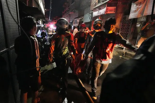 Indonesian rescue team carry a victim of fire at a neighborhood in Jakarta, Indonesia, Friday, March 3, 2023. A large fire broke out at a fuel storage depot in Indonesia's capital on Friday, killing several people, injuring dozens of others and forcing the evacuation of thousands of nearby residents after spreading to their neighborhood, officials said. (Photo by Achmad Ibrahim/AP Photo)