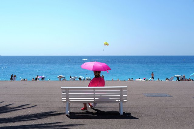 A woman sits on a bench in front of the Mediterranean sea on the “Promenade des Anglais” on the French riviera city of Nice, on July 16, 2025. (Photo by Valery Hache/AFP Photo)