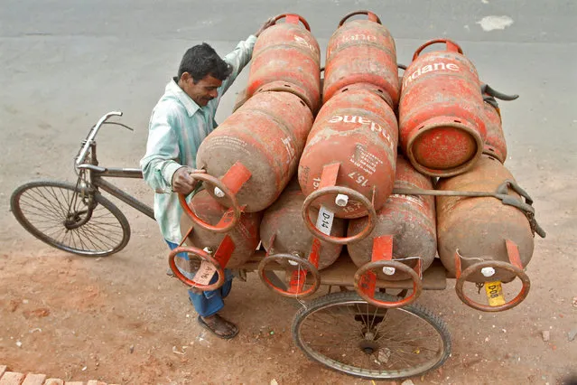 A worker loads Liquefied Petroleum Gas (LPG) cylinders onto his cycle-rickshaw in Kolkata January 17, 2013. (Photo by Rupak De Chowdhuri/Reuters)