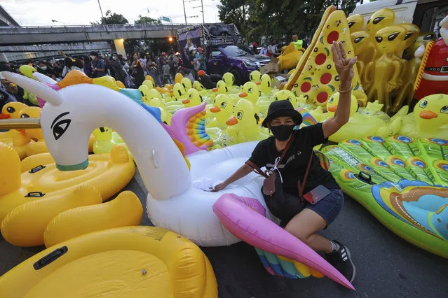 A woman flashes a three-finger protest gesture while posing in front of mostly inflatable yellow ducks, which have become good-humored symbols of resistance during anti-government rallies, November 27, 2020 in Bangkok, Thailand. (Photo by WasonWanichakorn/AP Photo)