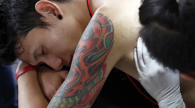 A young man gets a tattoo on her back during Bandung Body Art Festival at in Bandung, West Java, on December 7, 2014. (Photo by Rezza Estily/JG Photo)