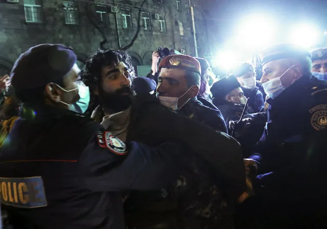 Armenian police officer detain a demonstrator during a rally to pressure Armenian Prime Minister Nikol Pashinyan to resign over a peace deal with neighboring Azerbaijan in Republic Square in Yerevan, Armenia, Thursday, December 3, 2020. In Armenia, the peace deal sparked outrage. Mass protests erupted in the capital Yerevan, with thousands regularly taking to the streets to demand the ouster of the country's prime minister. (Photo by Vahram Baghdasaryan/Photolure via AP Photo)